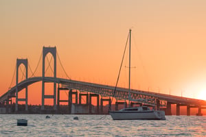 The Newport Bridge at sunset with a sailboat moored in the foreground