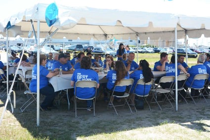 The Town Dock employees sitting at tables under a tent at the best places to work cookout
