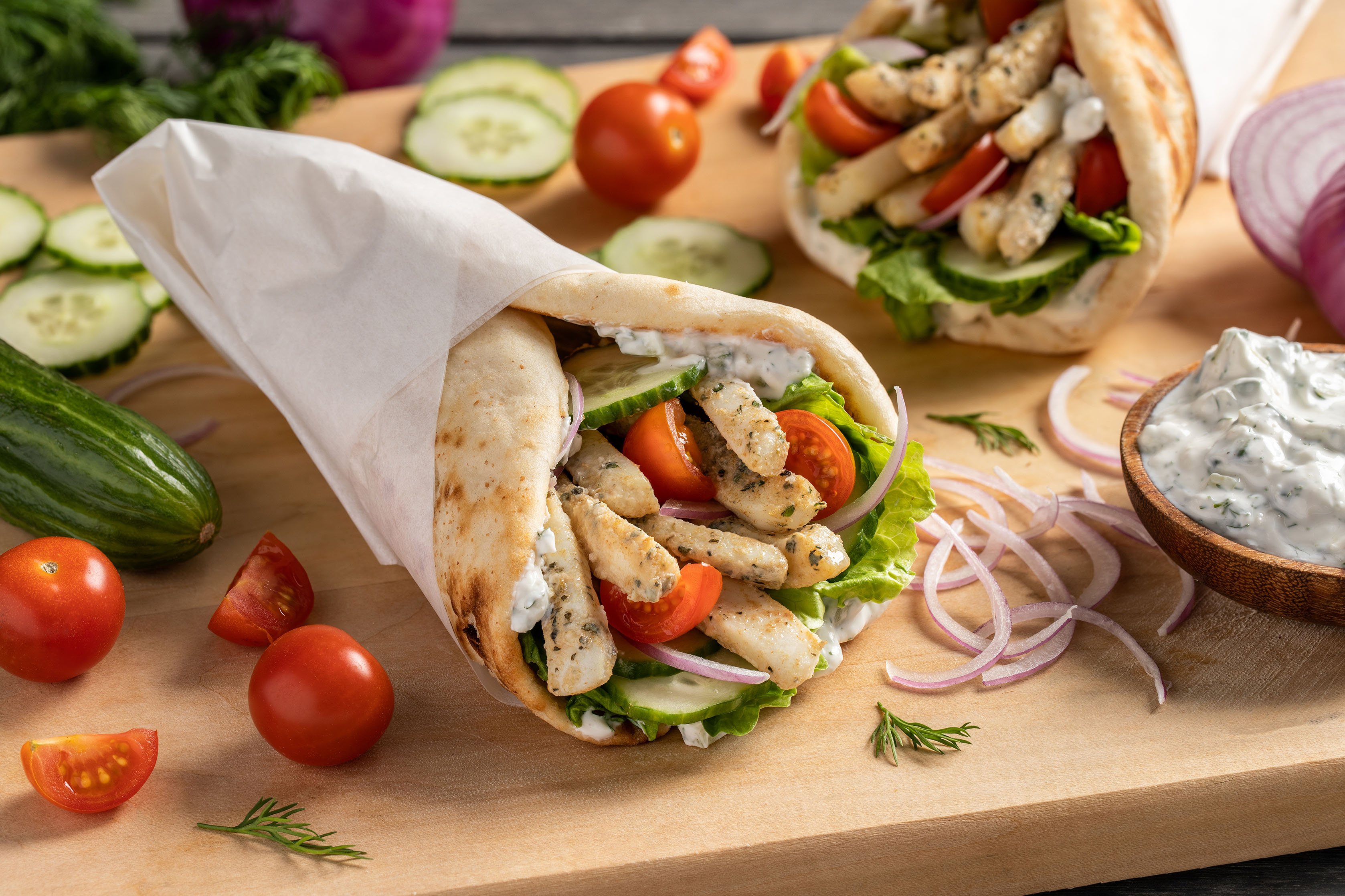 A gyro wrap with calamari strips, lettuce, tomato, tzatziki